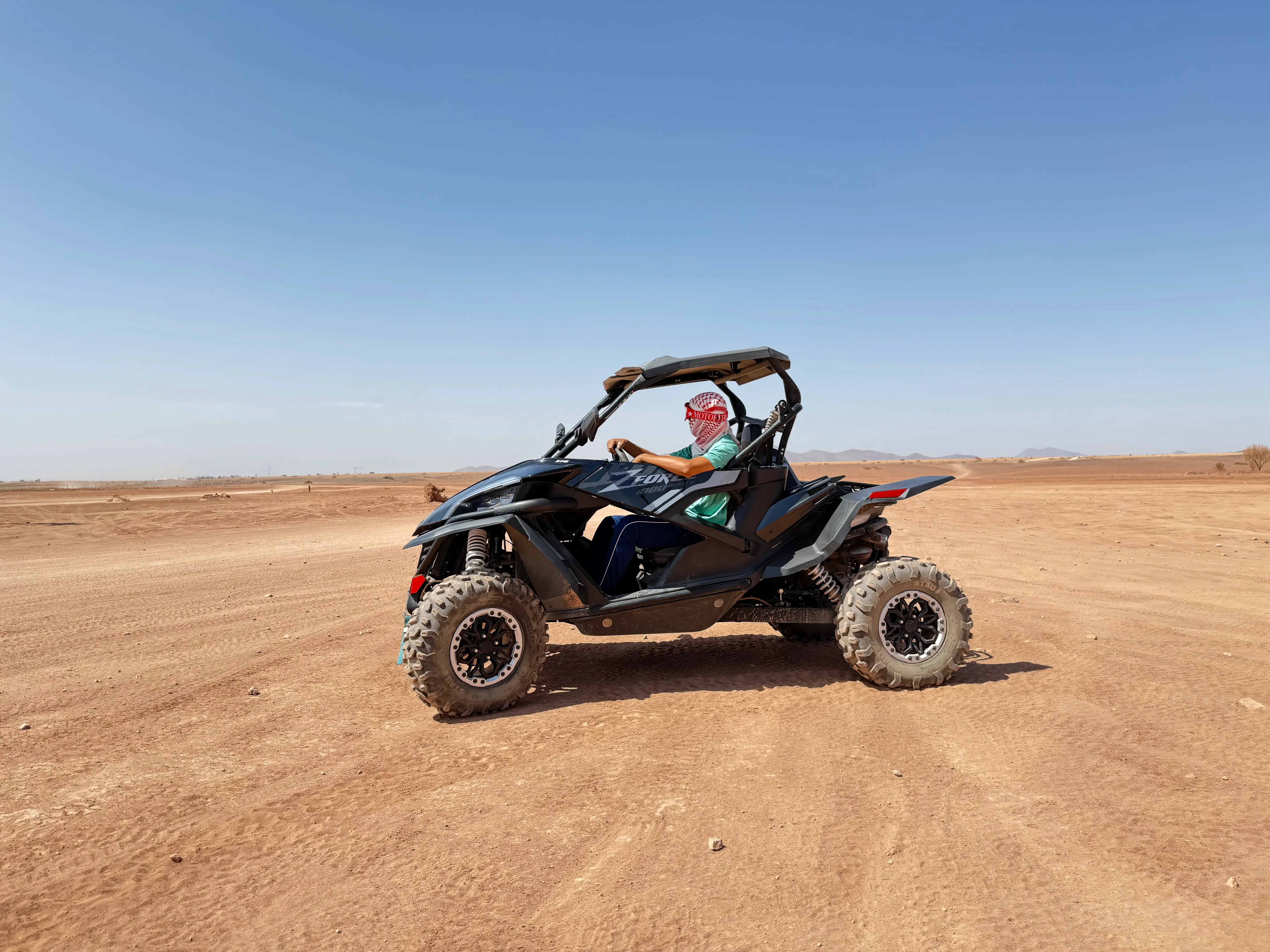 Client pilotant un buggy 1000cc à Marrakech dans le désert de la Palmeraie, avec masque et foulard pour une excursion buggy off-road