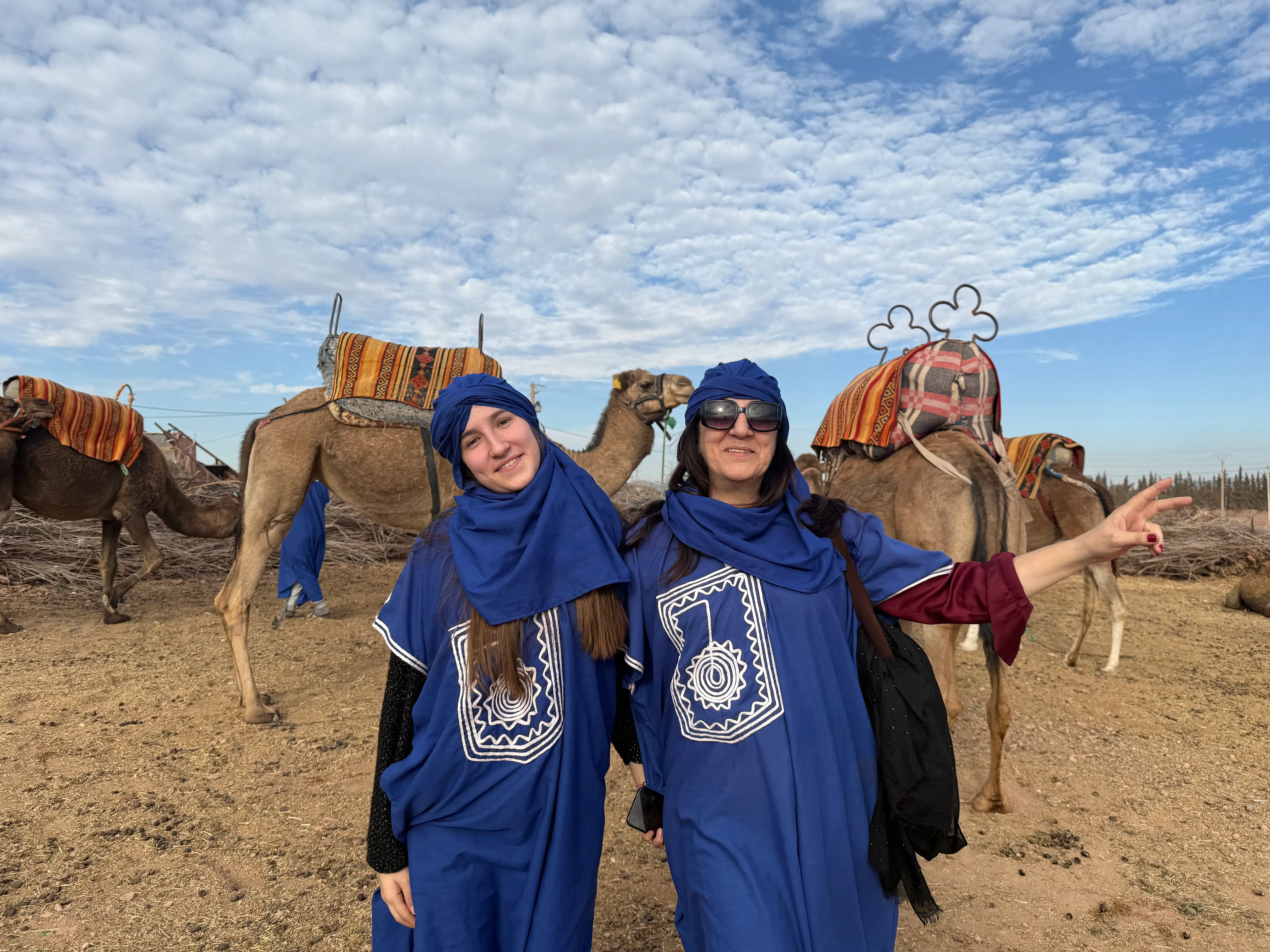 Père et sa fille portant une tenue traditionnelle marocaine pendant une balade à dos de dromadaire dans la Palmeraie de Marrakech.